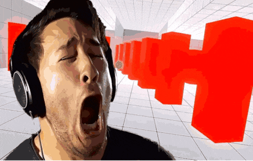 a man wearing headphones is yawning in front of a red cube