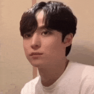 a young man is making a funny face while wearing a white shirt .