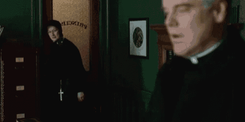 a priest is standing in front of a door that says ' secretary ' on it