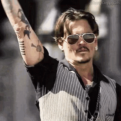 a man with a tattoo on his arm wearing sunglasses and a vest