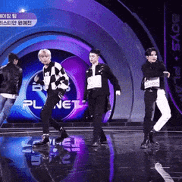 a group of people are dancing on a stage in front of a sign that says planet