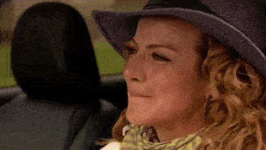 a woman wearing a hat is crying in a car .