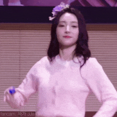 a woman in a pink shirt is dancing in front of a window .