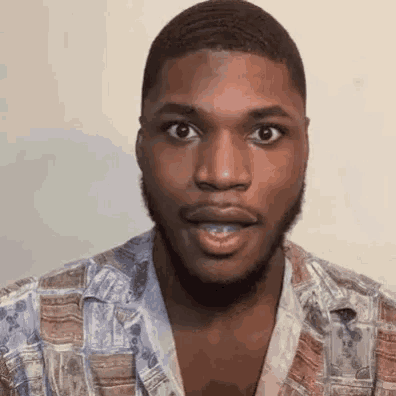 a man with a beard is making a surprised face while wearing a shirt .