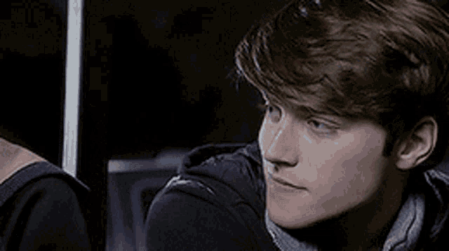 a close up of a young man 's face with a black jacket on