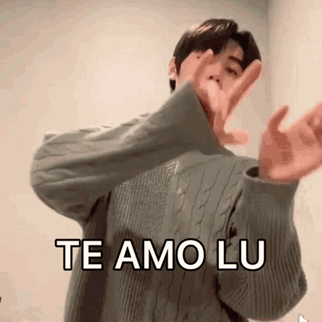 a man in a sweater is making a heart shape with his hands and says te amo lu