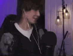 a man wearing headphones is standing in front of a microphone in a room .