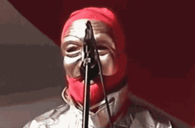 a person with a red mask on their face is singing into a microphone