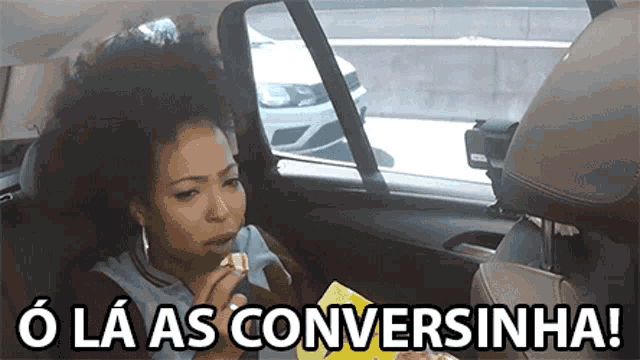 a woman is sitting in the back seat of a car and eating a snack .