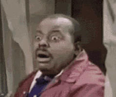 a man in a red jacket and blue tie is making a funny face .