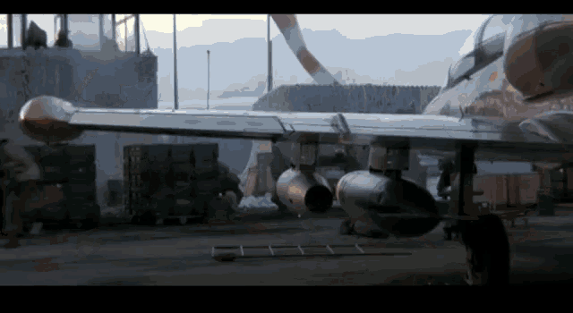 a fighter jet is parked on a runway with boxes behind it and a man standing next to it