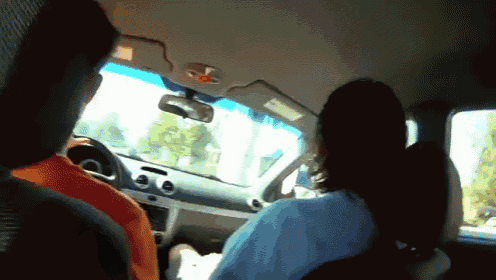 a woman is driving a car with a man in the back seat
