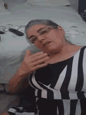a woman wearing glasses and a black and white striped dress is sitting on the floor