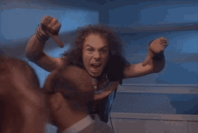 a man with long curly hair is giving a thumbs down sign