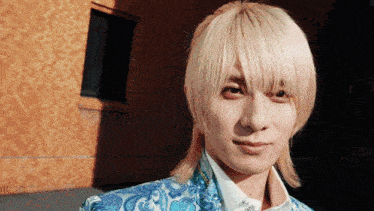 a man with blonde hair is wearing a blue jacket and white shirt