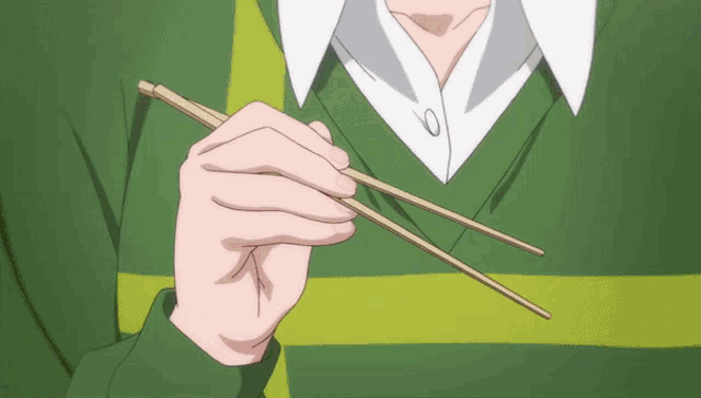a person in a green shirt is holding chopsticks in their right hand