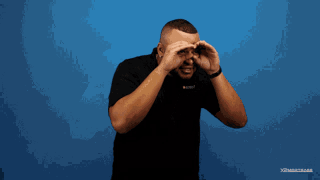 a man covering his eyes with his hands in front of a blue background that says xperimental