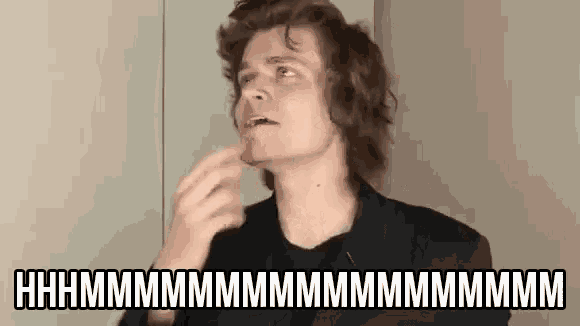 a man with long hair is making a funny face while holding his finger to his chin .