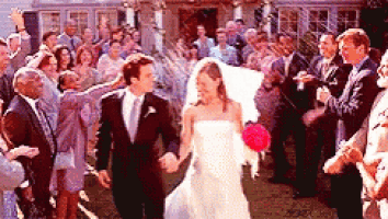 a bride and groom are walking down the aisle with their wedding guests .
