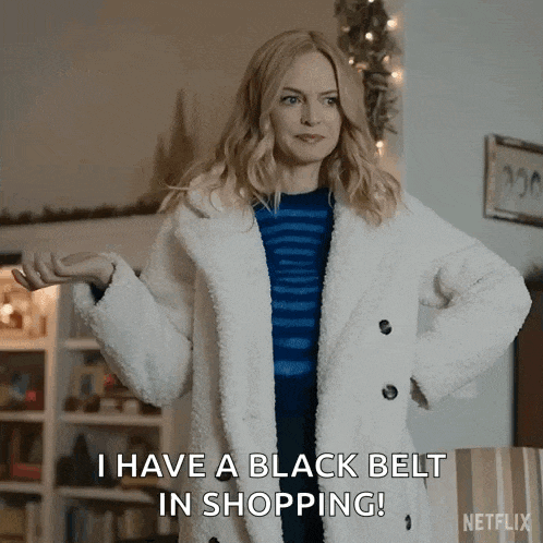a woman is wearing a white coat and a blue sweater and says `` i have a black belt in shopping '' .