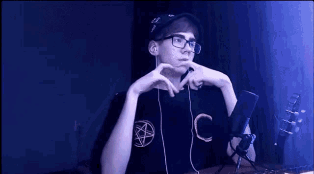 a young man is making a heart shape with his hands while wearing headphones and a hat .