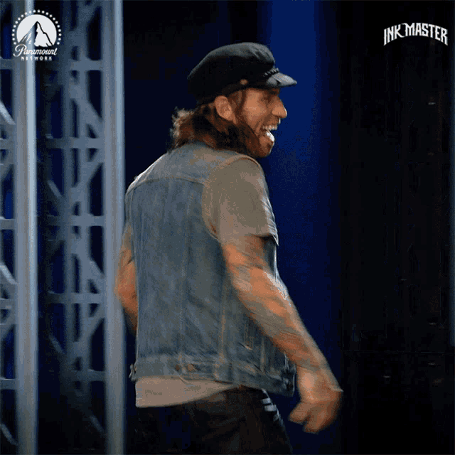 a man in a denim vest is dancing in front of a paramount network sign