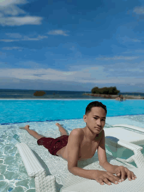 a young man laying on a raft in a pool