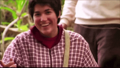 a man in a plaid shirt is smiling while being pushed by another person
