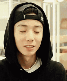 a young man wearing a black hoodie and a black hat