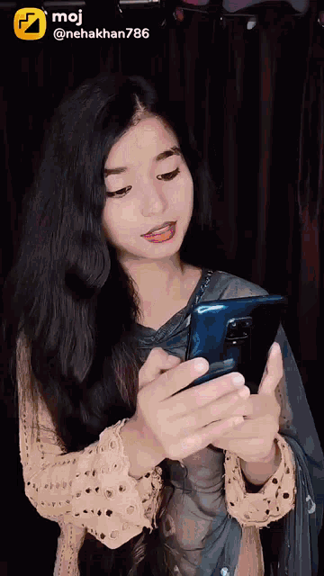 a woman is looking at her phone with the hashtag moj @nehakhan786 at the top