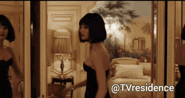 a woman in a black dress is standing in front of a mirror with the words @tvresidence written below her