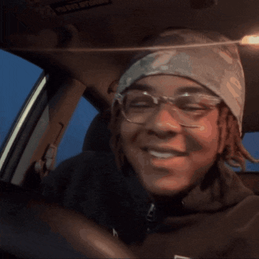 a young man wearing glasses and a headband driving a car