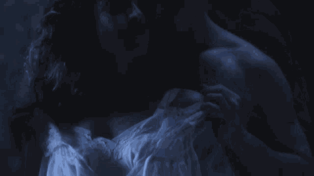 a woman in a white dress is being held in a dark room