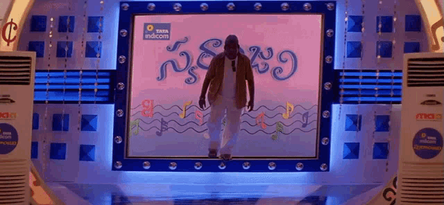 a man is standing in front of a large screen that says tata indicom