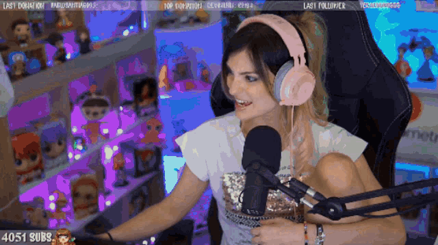 a woman wearing pink headphones is sitting in front of a microphone with the number 4051 on the bottom right