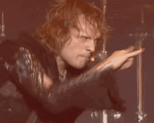 a man with red hair is singing into a microphone on stage