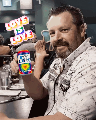 a man sitting at a table holding a can of boyd light beer