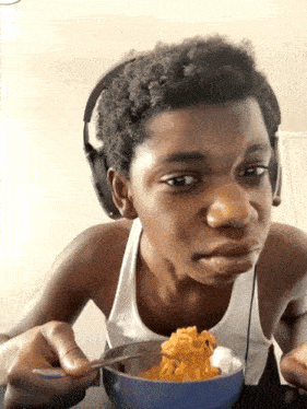 a young boy wearing headphones is eating a bowl of food