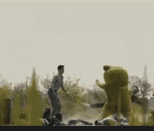 a man is standing in a field with a large yellow stuffed animal behind him