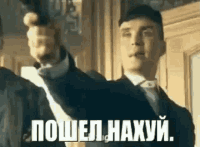a man in a suit and tie is pointing a gun at another man in a room in a foreign language .