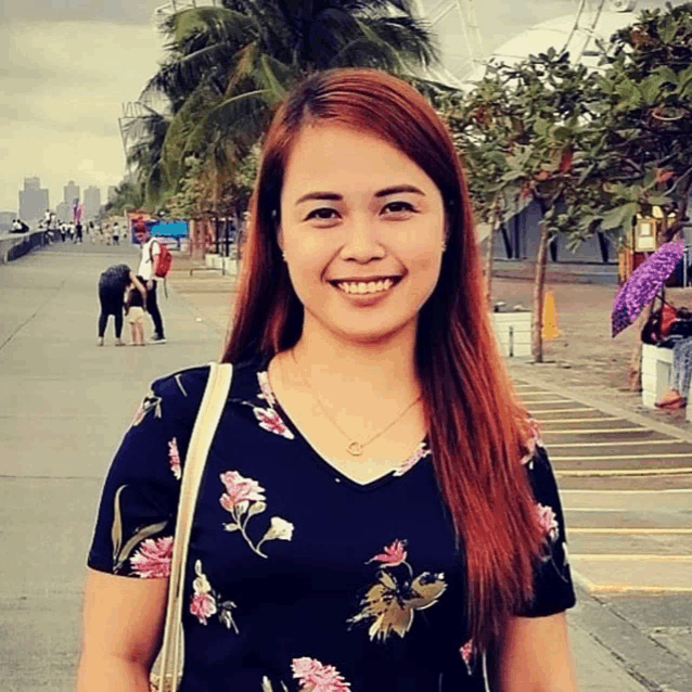 a woman wearing a floral shirt and a necklace smiles for the camera