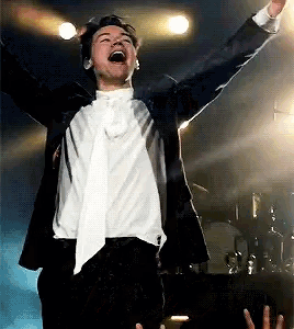 a man in a suit and tie is singing into a microphone on stage .