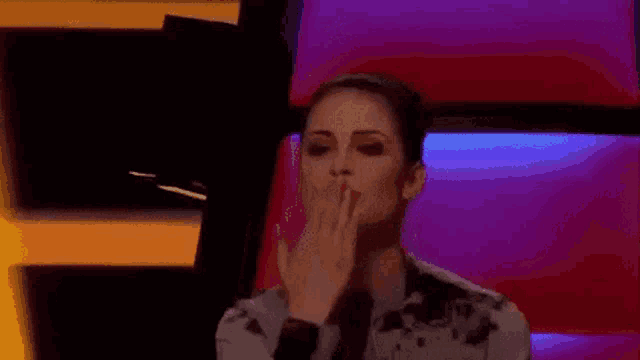 a woman is sitting in a chair with her hand on her mouth .