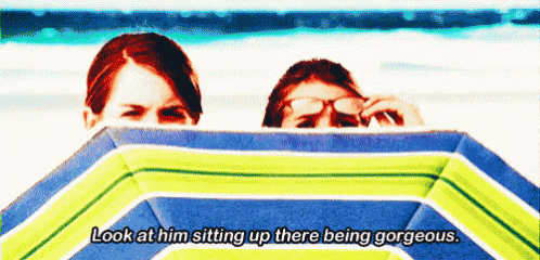 a man and a woman peeking out from behind a beach umbrella with a caption that says look at him sitting up
