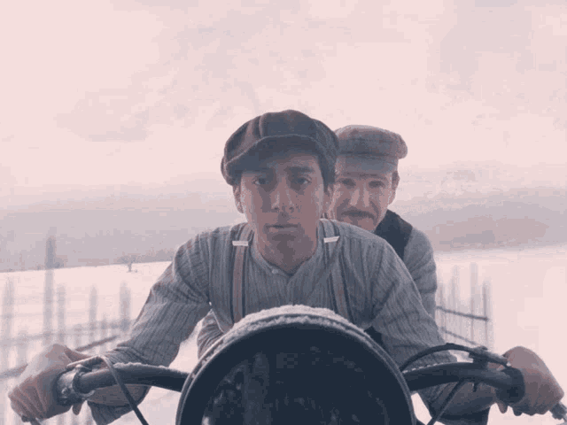 two men are riding a bike in the snow