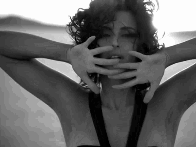 a black and white photo of a woman with her hands on her face