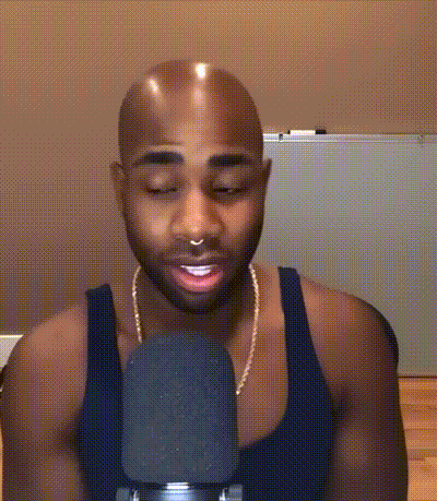 a man with a nose ring and a black tank top is talking into a microphone