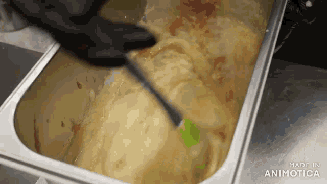 a container of food is being stirred with a spatula and the words made in animatica are on the bottom