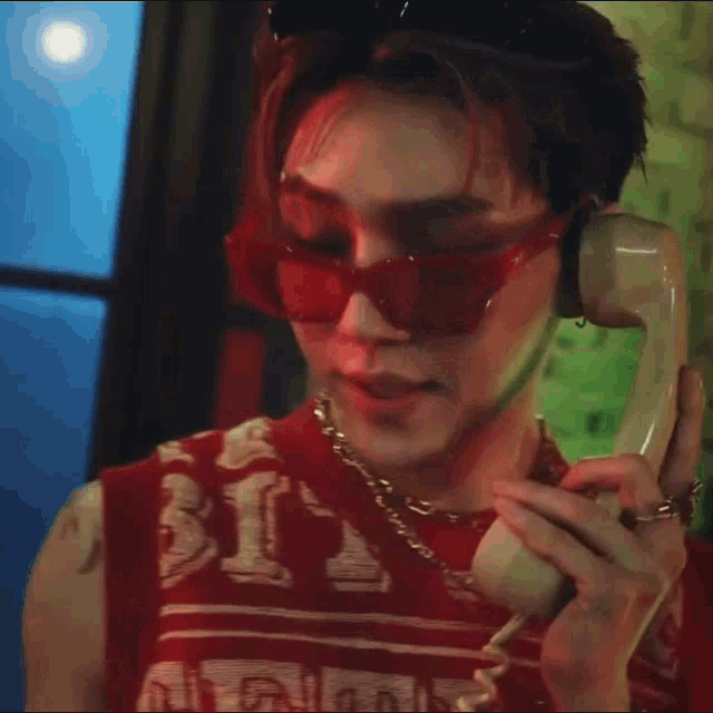a man wearing red sunglasses is talking on a cell phone .