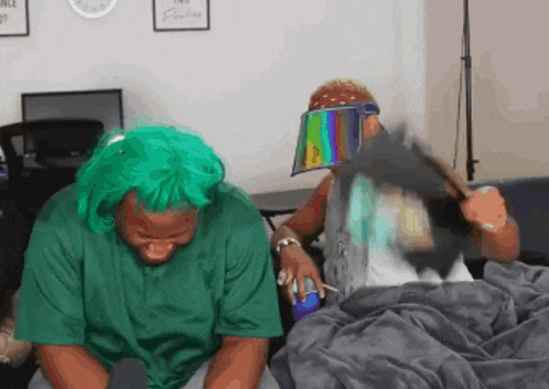 a man wearing a green wig is sitting next to another man wearing a rainbow visor